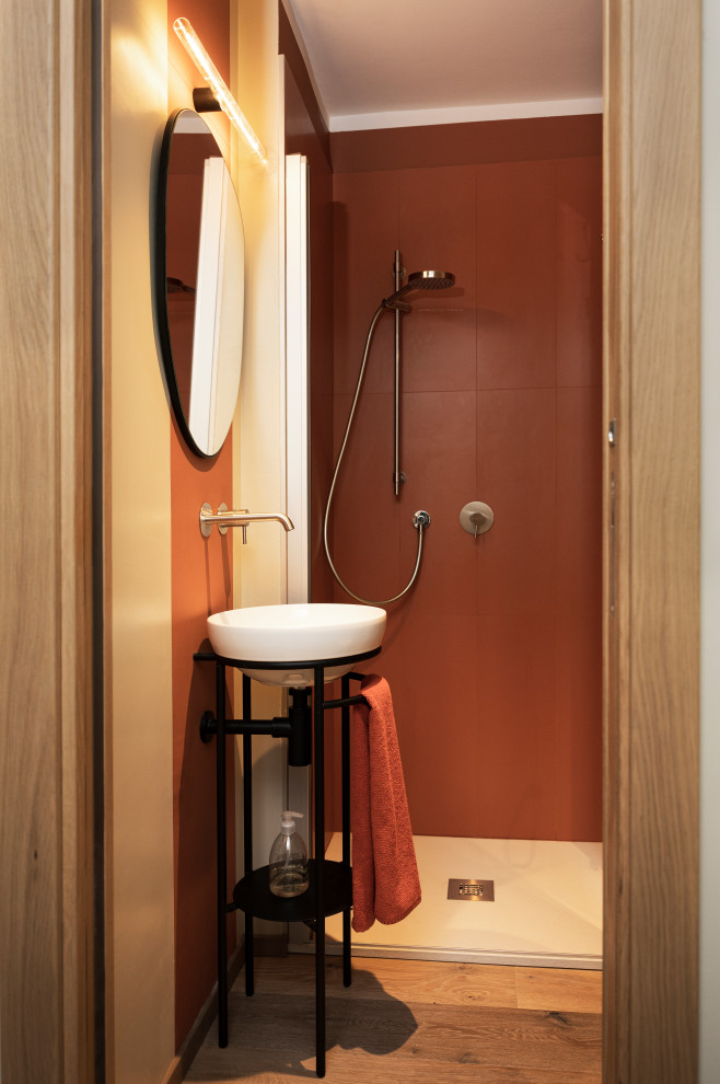 Modern inredning av ett litet toalett, med svarta skåp, röd kakel, porslinskakel och ljust trägolv