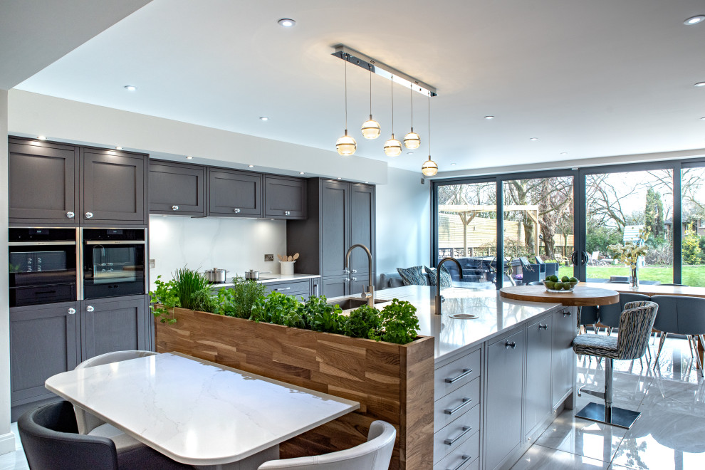 Photo of a large contemporary galley kitchen in Other with an undermount sink, shaker cabinets, grey cabinets, white splashback, stainless steel appliances, with island, white floor and white benchtop.