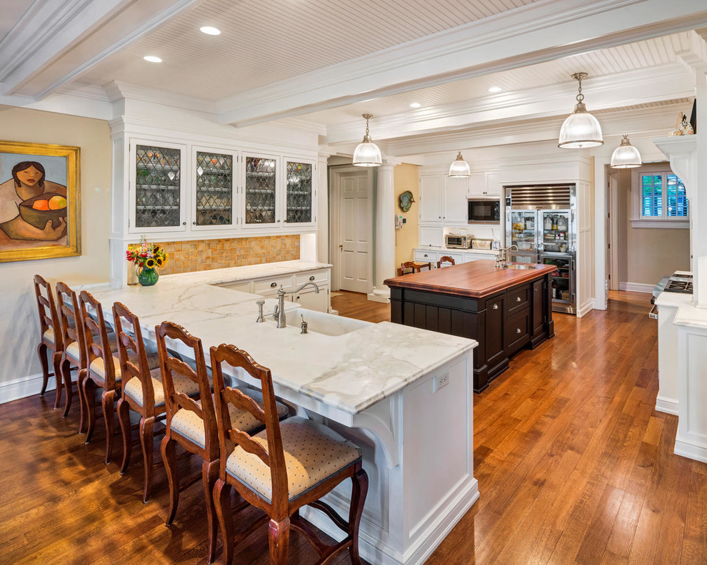 Traditional u-shaped kitchen in New York with a farmhouse sink, shaker cabinets, black cabinets, wood benchtops, yellow splashback, medium hardwood floors, multiple islands, brown floor and brown benchtop.