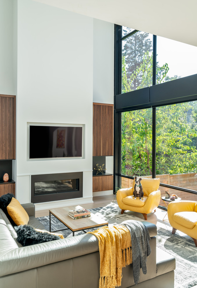Design ideas for a contemporary living room in Toronto with white walls, medium hardwood floors, a ribbon fireplace, a wall-mounted tv and brown floor.
