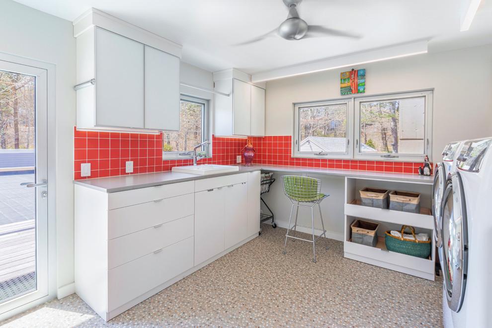 Photo of a contemporary dedicated laundry room in Boston with a drop-in sink, flat-panel cabinets, white cabinets, solid surface benchtops, beige walls, linoleum floors, a side-by-side washer and dryer, multi-coloured floor and grey benchtop.