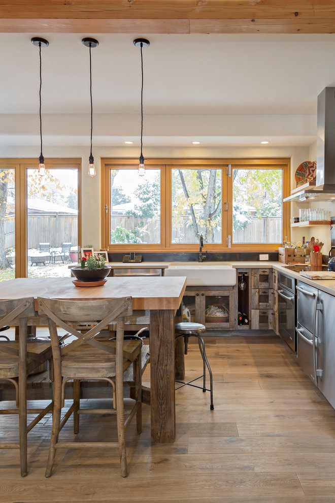 Photo of a contemporary single-wall eat-in kitchen in Denver with a farmhouse sink, shaker cabinets, distressed cabinets, brown splashback, metal splashback and stainless steel appliances.