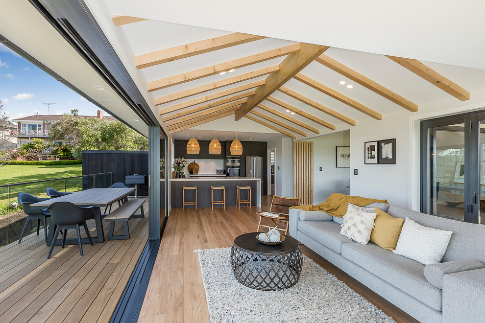 Mid-sized beach style U-shaped open plan kitchen in Auckland With an Undermount Sink, Flat-panel Cabinets, Dark Wood Cabinets, Quartz Benchtops, White Splashback, Porcelain Splashback, Stainless Steel Appliances, Light Hardwood Floors, a Peninsula and White Benchtop.