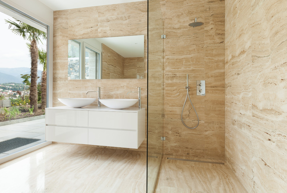 Inspiration for a large contemporary master bathroom in Malaga with flat-panel cabinets, white cabinets, a curbless shower, a wall-mount toilet, beige tile, marble, beige walls, marble floors, a vessel sink, solid surface benchtops, beige floor, a shower curtain, white benchtops and an alcove tub.