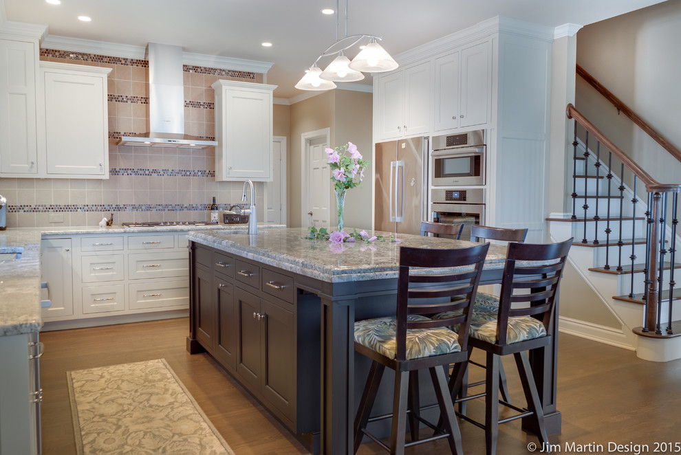 Mid-sized traditional u-shaped eat-in kitchen in Philadelphia with an undermount sink, recessed-panel cabinets, white cabinets, granite benchtops, grey splashback, ceramic splashback, stainless steel appliances, medium hardwood floors and with island.