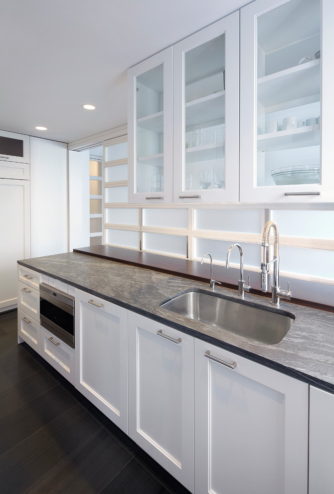 Photo of a mid-sized modern galley eat-in kitchen in New York with a single-bowl sink, shaker cabinets, white cabinets, granite benchtops, stainless steel appliances and a peninsula.