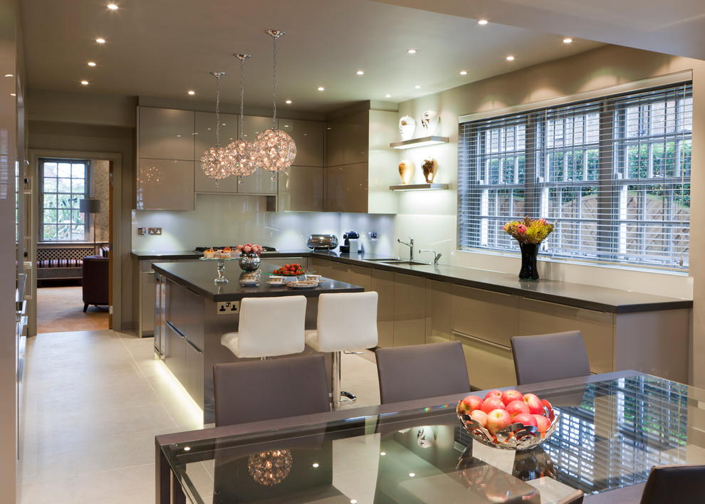 This is an example of a large contemporary u-shaped eat-in kitchen in London with an undermount sink, flat-panel cabinets, white splashback, stainless steel appliances, ceramic floors and with island.