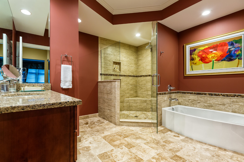 Photo of a large traditional master bathroom in Detroit with an undermount sink, shaker cabinets, an alcove tub, a corner shower, a two-piece toilet, medium wood cabinets, engineered quartz benchtops, multi-coloured tile, stone tile, red walls, travertine floors, beige floor and a hinged shower door.