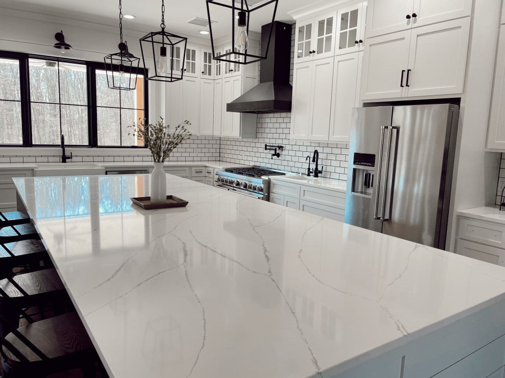 Inspiration for a large modern eat-in kitchen in Chicago with a farmhouse sink, quartz benchtops, white splashback, subway tile splashback, stainless steel appliances, medium hardwood floors, with island, brown floor, white benchtop and exposed beam.