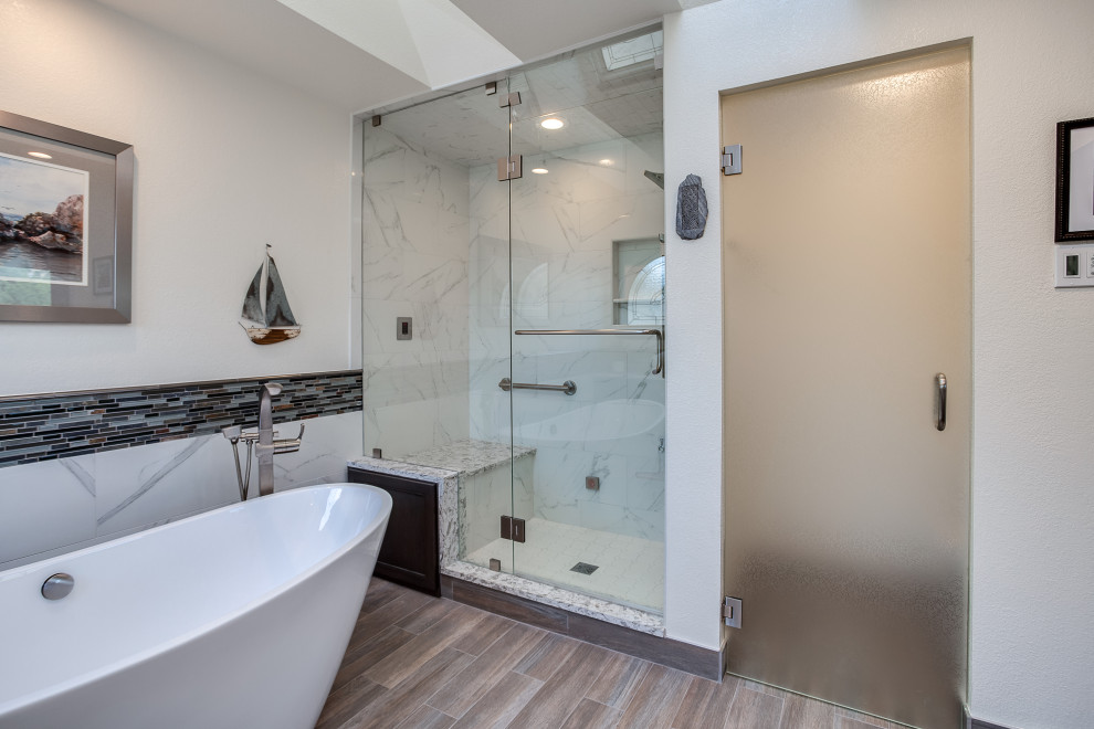 Photo of a large contemporary ensuite bathroom in Denver with shaker cabinets, brown cabinets, a japanese bath, a built-in shower, grey tiles, white walls, medium hardwood flooring, an integrated sink, granite worktops, brown floors, a hinged door, white worktops, a shower bench, double sinks and a built in vanity unit.