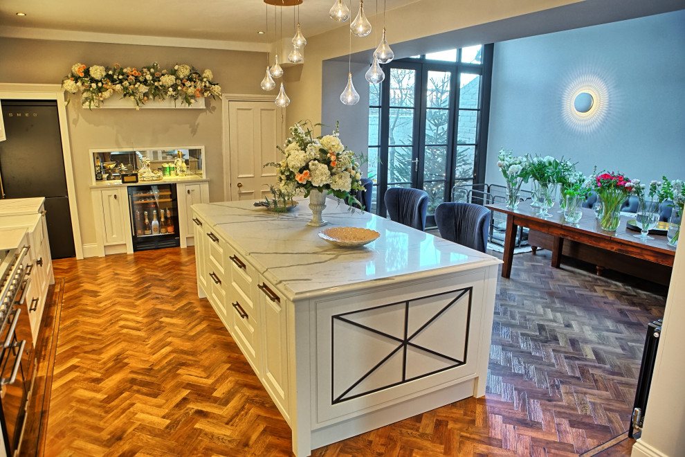 Inspiration for a large traditional l-shaped eat-in kitchen in Other with a farmhouse sink, recessed-panel cabinets, medium wood cabinets, marble benchtops, glass sheet splashback, black appliances, vinyl floors and with island.