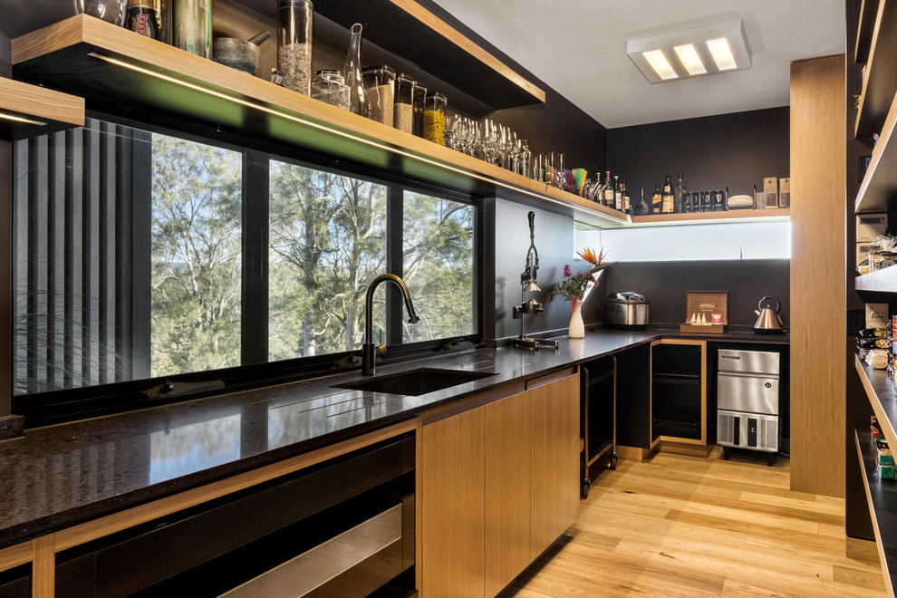 Large contemporary galley kitchen in Brisbane with an integrated sink, black cabinets and quartz benchtops.