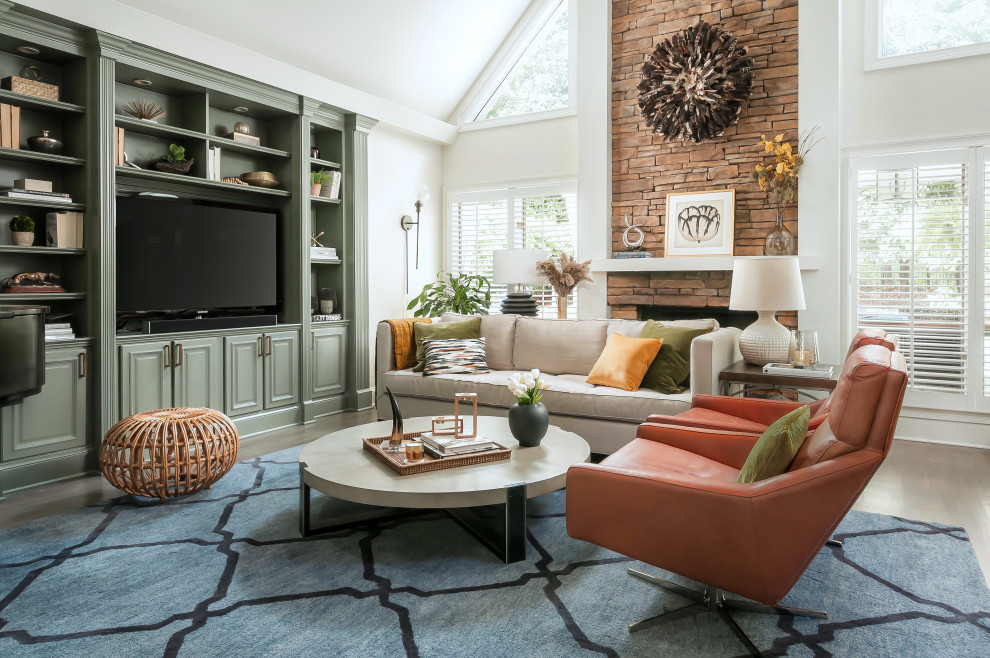 Cette image montre un grand salon design ouvert avec un mur blanc, un sol en bois brun, une cheminée standard, un manteau de cheminée en pierre, un téléviseur encastré, un sol gris et un plafond voûté.