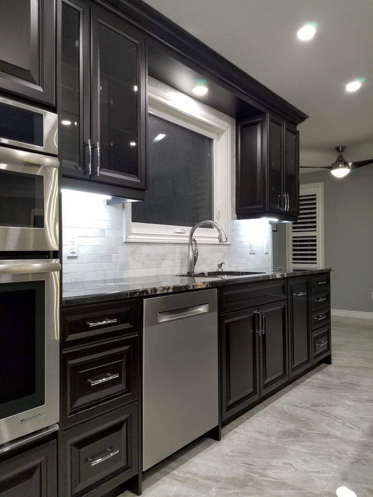 Inspiration for a modern galley gray floor eat-in kitchen remodel in Toronto with an undermount sink, raised-panel cabinets, dark wood cabinets, gray backsplash, stainless steel appliances, an island and multicolored countertops
