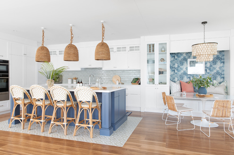 Large beach style l-shaped eat-in kitchen in Gold Coast - Tweed with shaker cabinets, white cabinets, with island, white benchtop, a single-bowl sink, quartz benchtops, green splashback, porcelain splashback, stainless steel appliances, porcelain floors and beige floor.