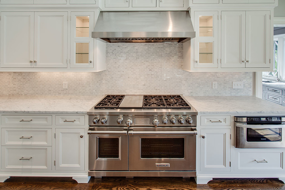 Mid-sized transitional l-shaped dark wood floor and brown floor eat-in kitchen photo with an undermount sink, recessed-panel cabinets, white cabinets, white backsplash, stainless steel appliances, an island and marble countertops