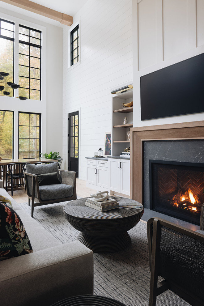 This is an example of a large transitional formal open concept living room in Grand Rapids with white walls, light hardwood floors, a standard fireplace, a tile fireplace surround, a wall-mounted tv, beige floor, exposed beam and planked wall panelling.