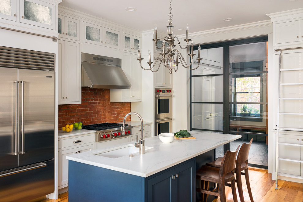 Inspiration for a traditional l-shaped eat-in kitchen in Boston with an undermount sink, shaker cabinets, marble benchtops, stainless steel appliances, light hardwood floors and with island.