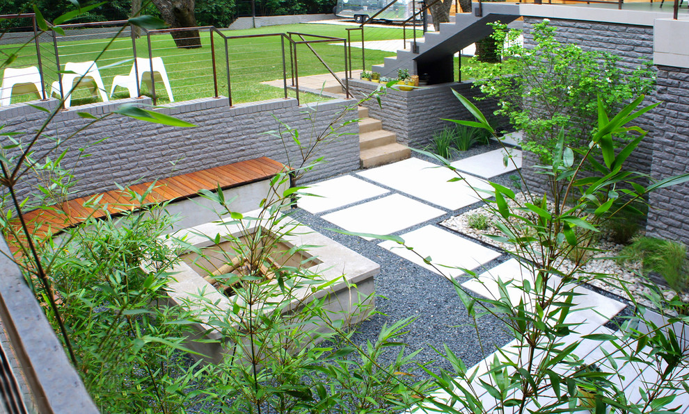Small modern backyard partial sun xeriscape in Austin with concrete pavers.