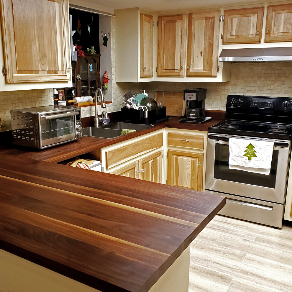 Bild på ett mellanstort vintage brun brunt kök, med en dubbel diskho, luckor med upphöjd panel, gula skåp, träbänkskiva, brunt stänkskydd, stänkskydd i trä, rostfria vitvaror, ljust trägolv och beiget golv