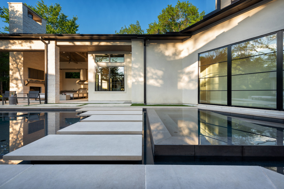 Large contemporary backyard custom-shaped infinity pool in Dallas with concrete slab.
