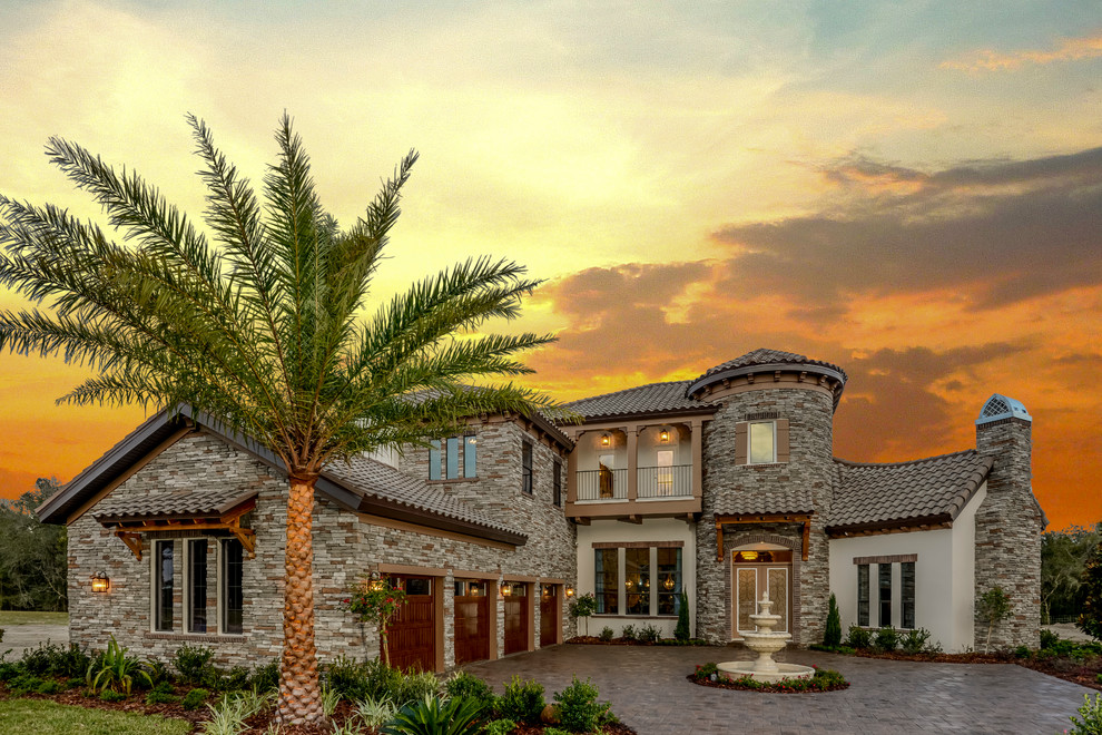 Expansive mediterranean two-storey grey exterior in Tampa with stone veneer.