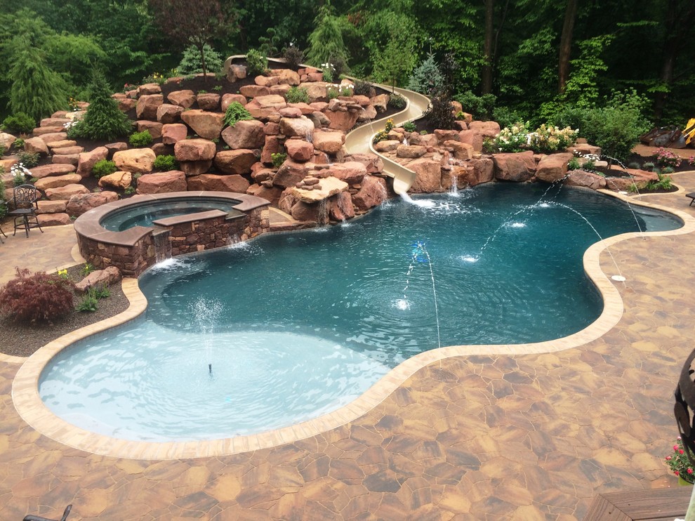 Photo of a large traditional backyard custom-shaped natural pool in Philadelphia with a water slide and concrete pavers.