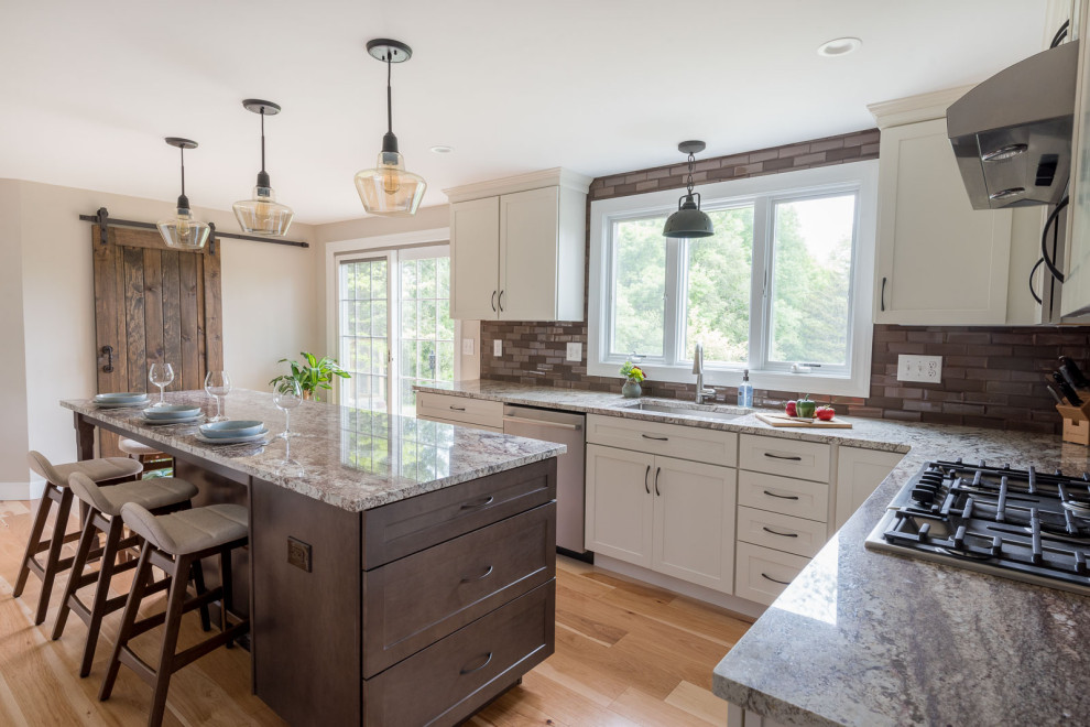 Mid-sized transitional u-shaped light wood floor and brown floor eat-in kitchen photo in Boston with an undermount sink, shaker cabinets, white cabinets, granite countertops, brown backsplash, glass tile backsplash, stainless steel appliances, an island and multicolored countertops