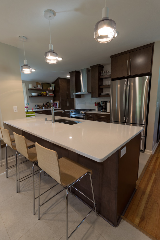 Midcentury open plan kitchen in Minneapolis with a double-bowl sink, dark wood cabinets, quartz benchtops, white splashback, stainless steel appliances, ceramic floors, a peninsula and beige floor.