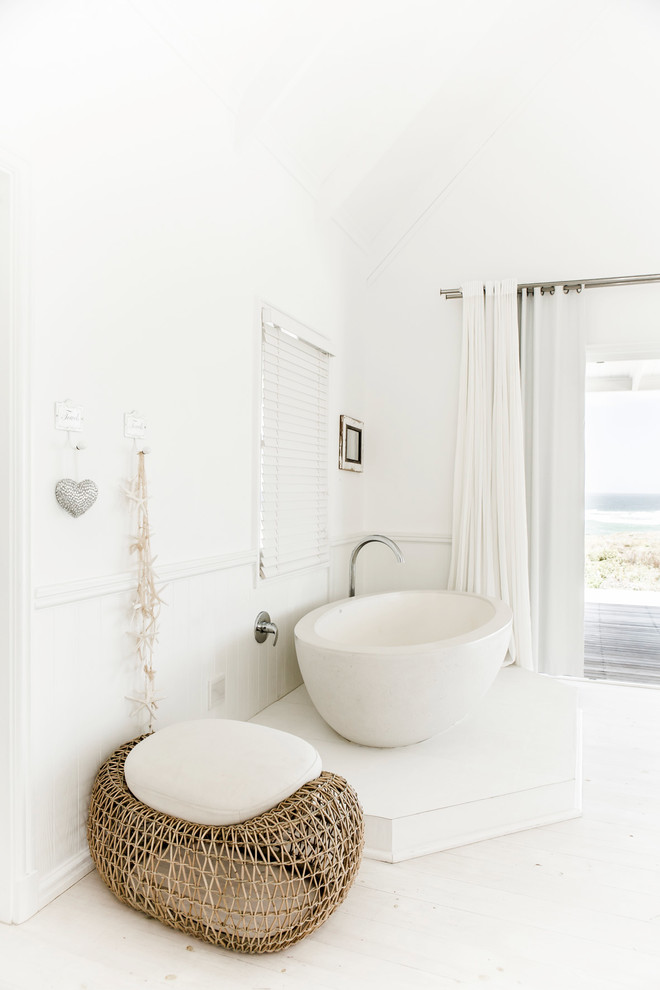 Photo of a mid-sized beach style bathroom in Other with a freestanding tub, white walls and painted wood floors.