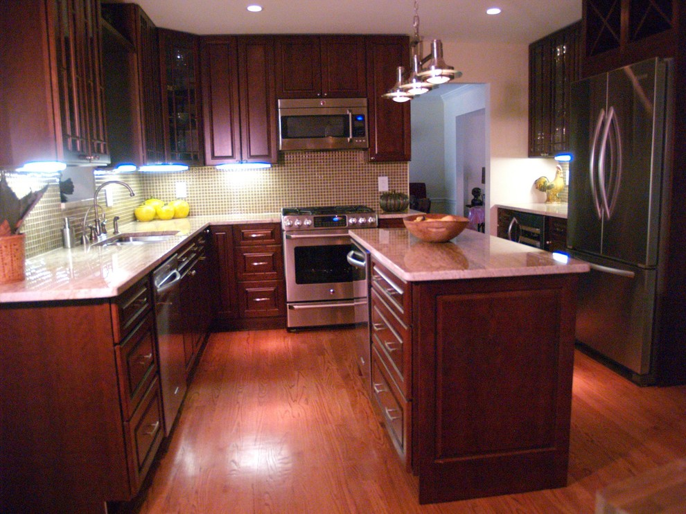 Mid-sized transitional l-shaped medium tone wood floor eat-in kitchen photo in DC Metro with a drop-in sink, raised-panel cabinets, dark wood cabinets, granite countertops, green backsplash, glass sheet backsplash, stainless steel appliances and an island