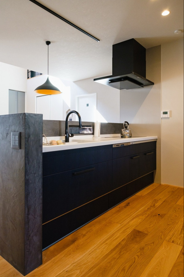 Cette image montre une cuisine ouverte avec des portes de placard bleues, un sol en bois brun, un sol marron et un plafond en papier peint.