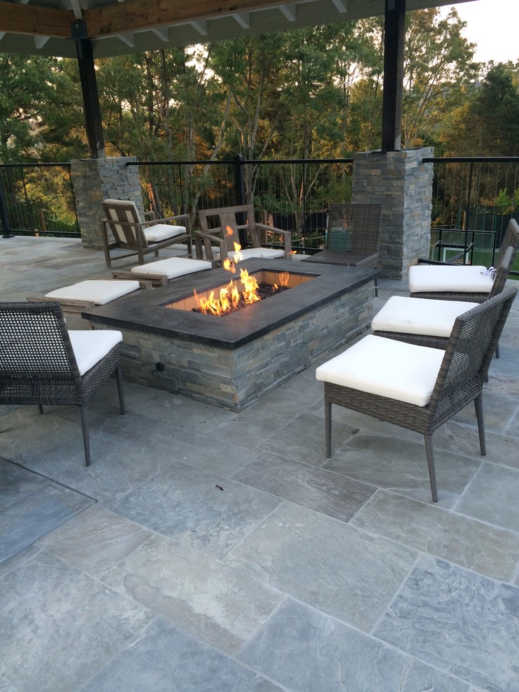 Photo of a large contemporary backyard patio in Other with a fire feature, stamped concrete and a roof extension.