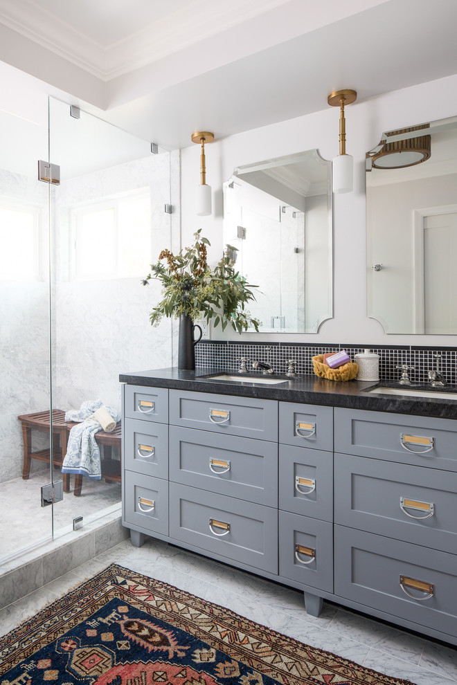 This is an example of a large transitional master bathroom in Los Angeles with shaker cabinets, grey cabinets, a one-piece toilet, black tile, stone tile, white walls, marble floors, an undermount sink, marble benchtops, an alcove shower and a hinged shower door.