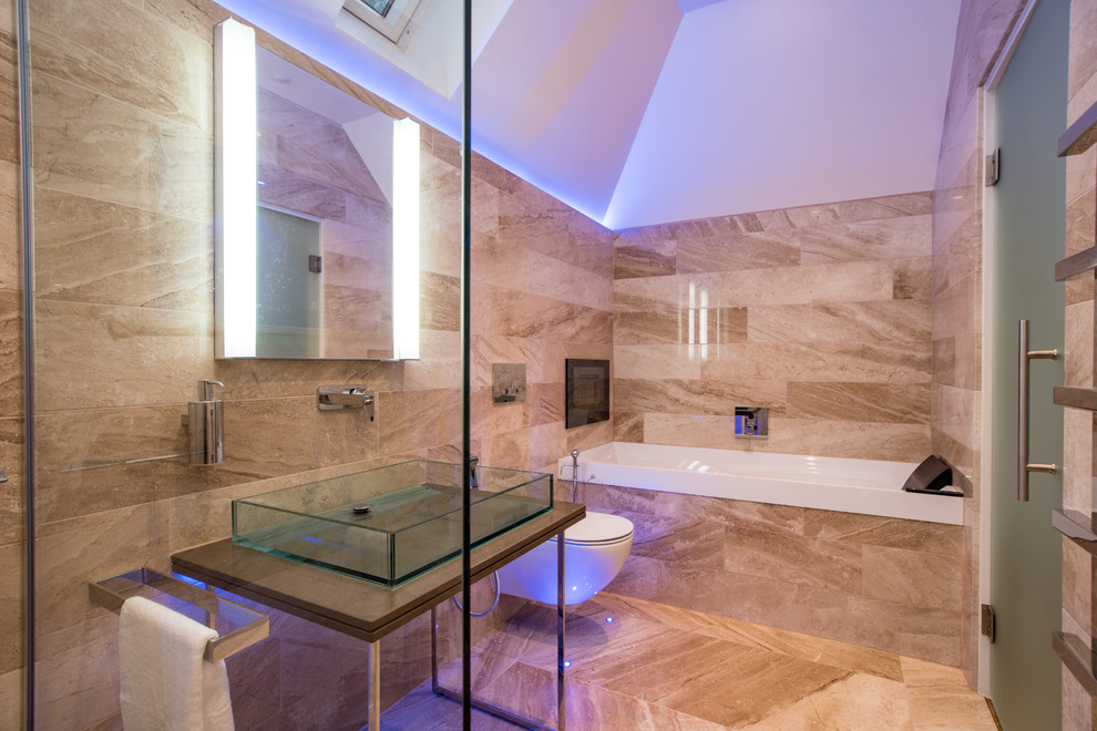 Photo of a contemporary master bathroom in Buckinghamshire with a wall-mount toilet, beige tile, beige walls, a vessel sink, beige floor, a hinged shower door, brown benchtops, a corner tub, an open shower and marble.