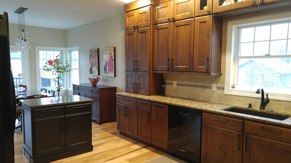 Mid-sized transitional light wood floor eat-in kitchen photo with an undermount sink, recessed-panel cabinets, dark wood cabinets, quartz countertops, beige backsplash, ceramic backsplash, black appliances and an island