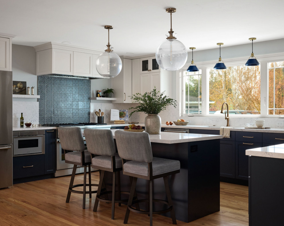 Large transitional u-shaped medium tone wood floor and brown floor open concept kitchen photo with a single-bowl sink, shaker cabinets, blue cabinets, quartz countertops, blue backsplash, quartz backsplash, stainless steel appliances, an island and blue countertops