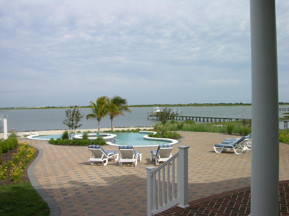 Large transitional backyard concrete paver and custom-shaped hot tub photo