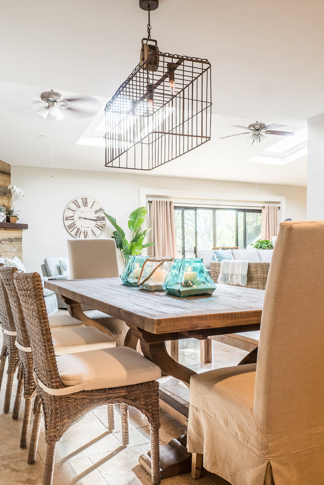 Photo of a mid-sized beach style open plan dining in San Diego with white walls, ceramic floors, a standard fireplace, a wood fireplace surround and beige floor.