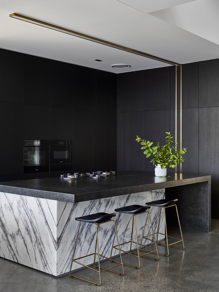 Inspiration for a mid-sized modern l-shaped eat-in kitchen in Sunshine Coast with flat-panel cabinets, concrete floors, with island, grey floor, a single-bowl sink, dark wood cabinets, granite benchtops, window splashback, black appliances and black benchtop.