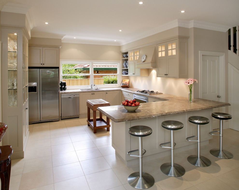 Photo of a transitional u-shaped eat-in kitchen in Sydney with a drop-in sink, recessed-panel cabinets, white cabinets, granite benchtops, beige splashback, stainless steel appliances, beige walls, ceramic floors and no island.