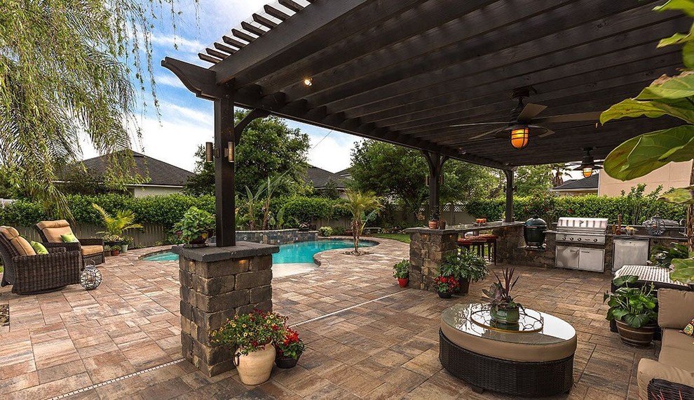 Large transitional backyard patio in Tampa with an outdoor kitchen, stamped concrete and a pergola.