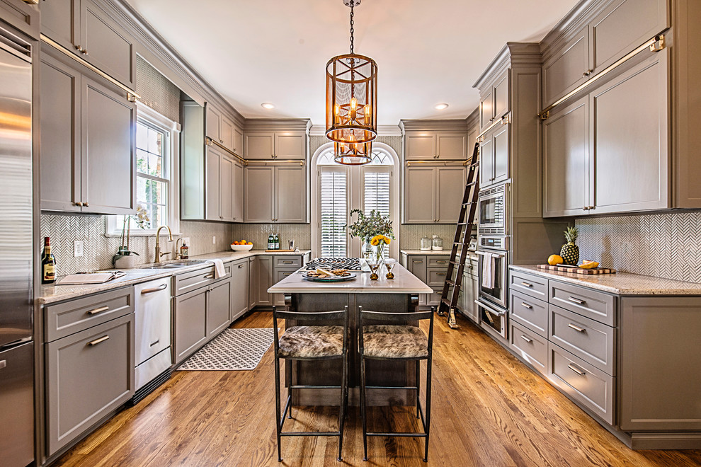 Large transitional u-shaped medium tone wood floor and brown floor enclosed kitchen photo in Nashville with an undermount sink, recessed-panel cabinets, gray cabinets, granite countertops, white backsplash, mosaic tile backsplash, stainless steel appliances, an island and multicolored countertops