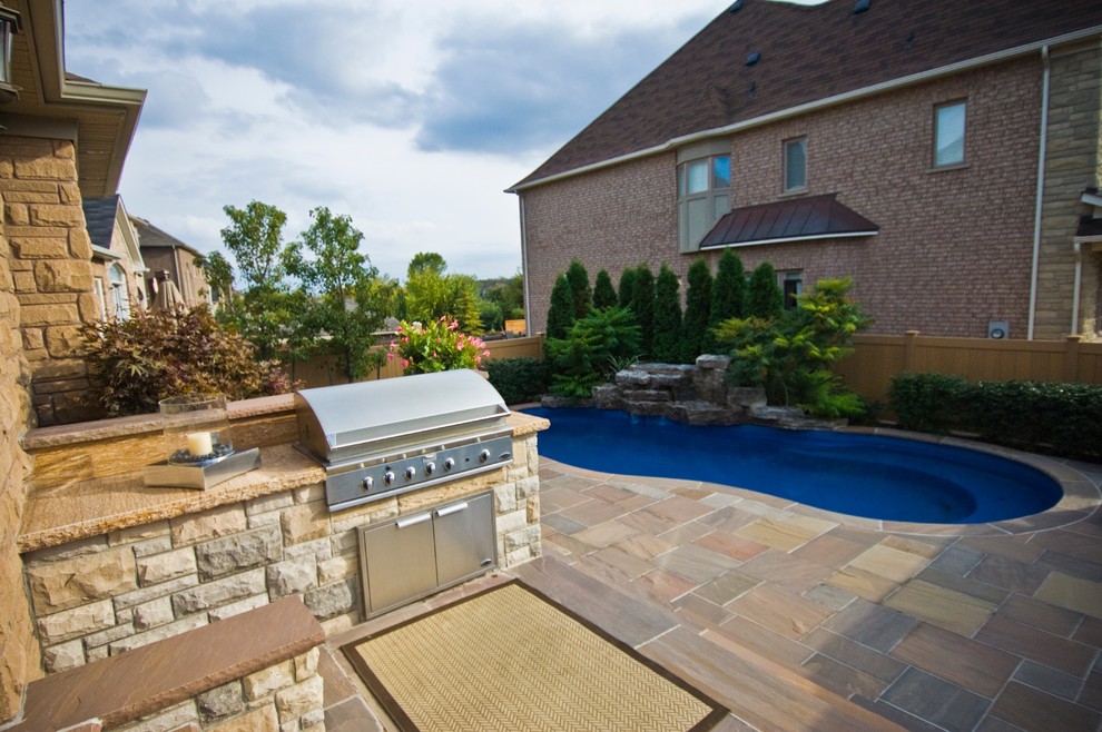 Patio kitchen - transitional backyard stone patio kitchen idea in Toronto