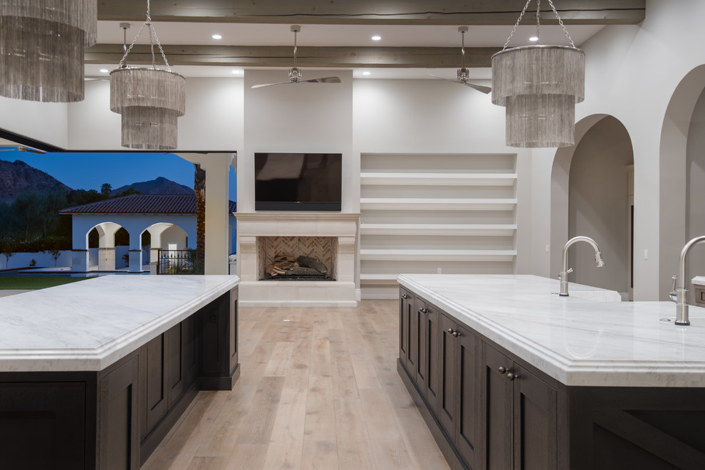 Design ideas for a large contemporary open plan kitchen in Phoenix with a drop-in sink, brown cabinets, white splashback, black appliances, medium hardwood floors, multiple islands, brown floor, white benchtop, recessed-panel cabinets and quartzite benchtops.