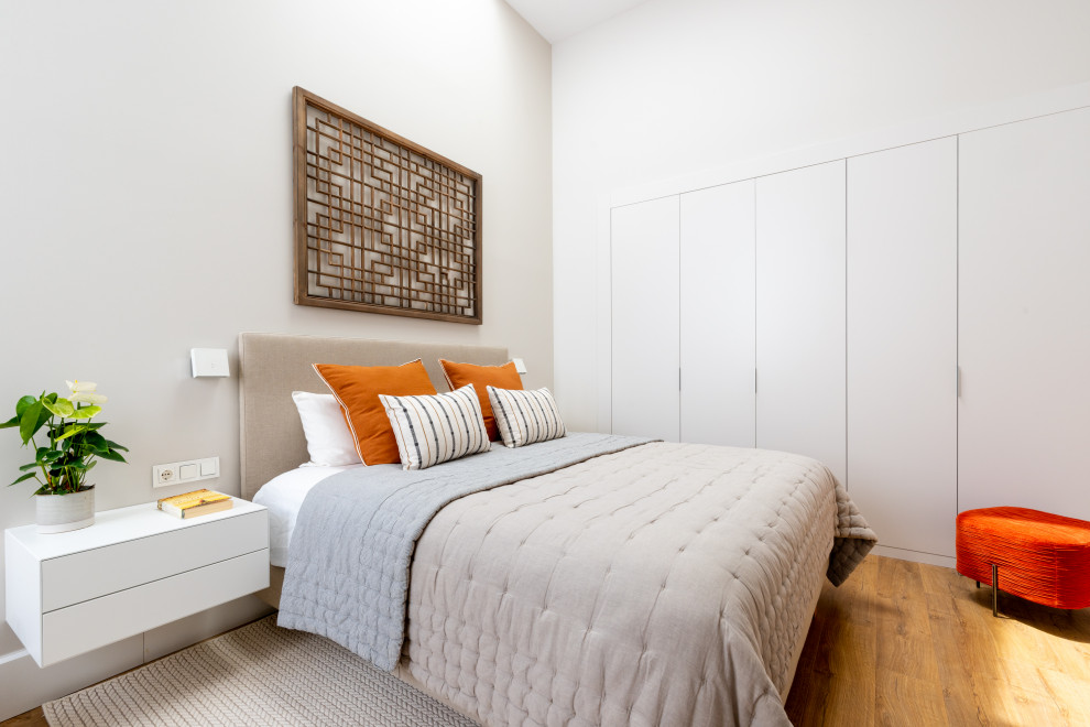 Idee per una camera matrimoniale design di medie dimensioni con pareti bianche, pavimento in legno massello medio e pavimento marrone