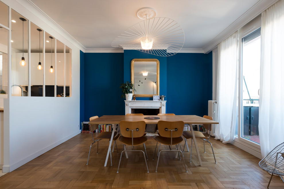 Inspiration for a large midcentury open plan dining in Grenoble with blue walls, light hardwood floors, a standard fireplace, a stone fireplace surround and brown floor.