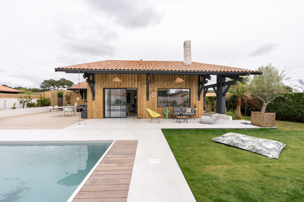 Aménagement d'un grand piscine avec aménagement paysager arrière bord de mer rectangle avec une terrasse en bois.