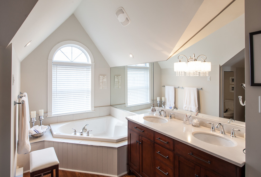 Photo of a traditional bathroom in Other with an undermount sink, shaker cabinets, dark wood cabinets, a corner tub and white tile.