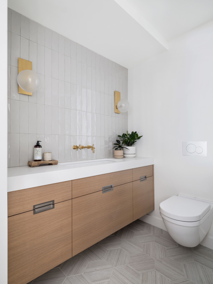 Photo of a mid-sized scandinavian master bathroom in San Diego with flat-panel cabinets, light wood cabinets, an alcove tub, a shower/bathtub combo, a one-piece toilet, gray tile, porcelain tile, white walls, porcelain floors, an undermount sink, engineered quartz benchtops, grey floor, a hinged shower door, white benchtops, a single vanity and a built-in vanity.